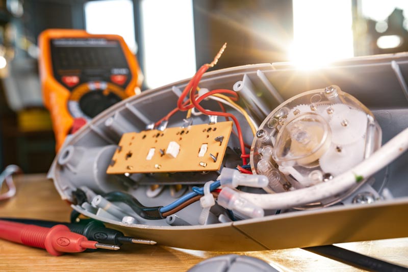 Close-up of iron motor from home cooling fan lies on a table under repair